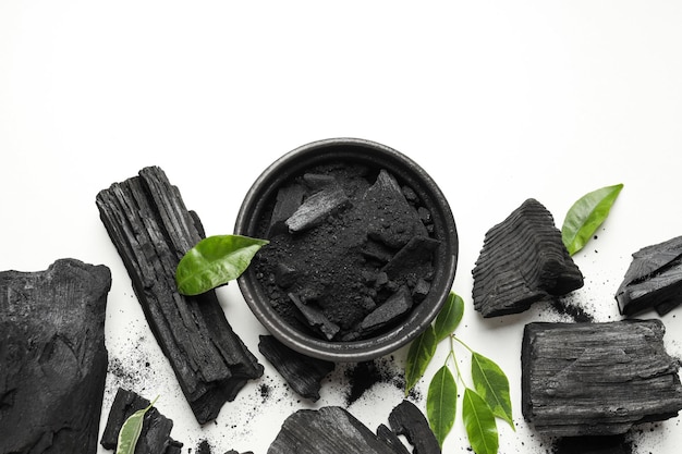 Foto carvão em pó de carvão e folhas no fundo branco