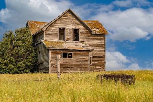 Casa abandonada em um pátio em Saskatchewan, Canadá, com arame farpado em primeiro plano