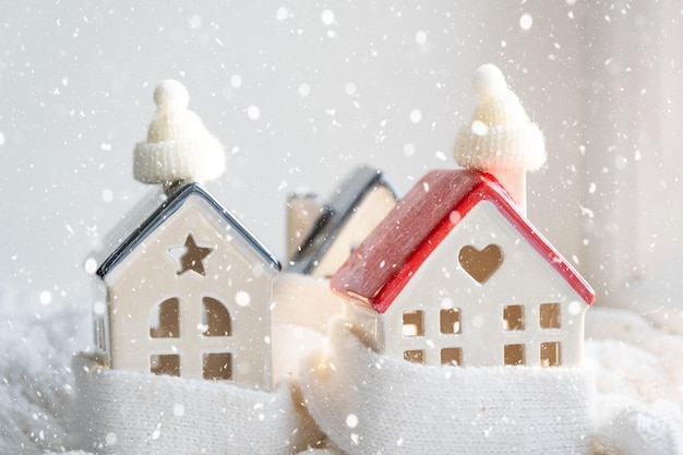 Casa aconchegante é embrulhada em um chapéu e cachecol em uma decoração de peitoril de janela de tempestade de neve Isolamento de casa de neve de inverno proteção contra frio e mau tempo sistema de aquecimento de ambiente Clima festivo Natal Ano novo