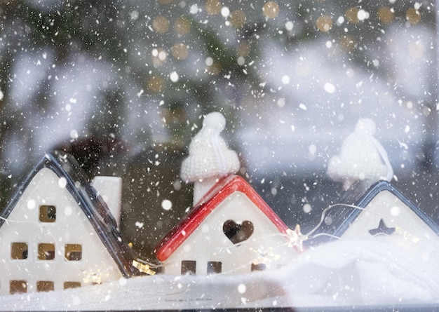 Casa aconchegante é embrulhada em um chapéu e cachecol em uma decoração de peitoril de janela de tempestade de neve Isolamento de casa de neve de inverno proteção contra frio e mau tempo sistema de aquecimento de ambiente Clima festivo Natal Ano novo