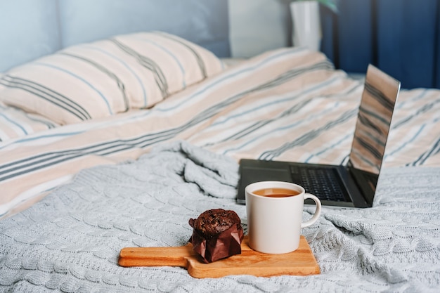 Casa aconchegante, interior e inverno, quarto conceito com laptop, xícara de café e muffin