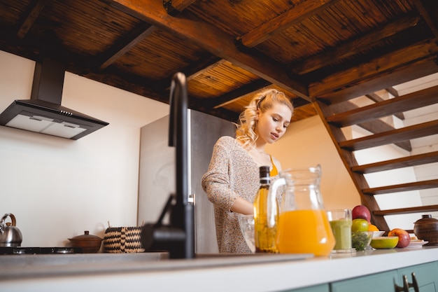 Casa aconchegante. Menina bonita baixando a cabeça enquanto olha para a mesa