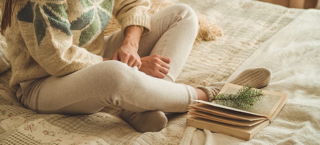 Casa aconchegante. Mulher bonita está lendo um livro na cama. Bom dia com chá e livro. Bela jovem relaxante. O conceito de leitura