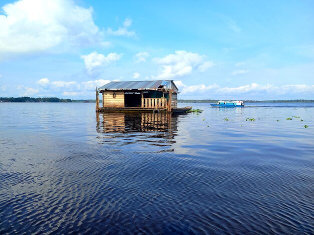 Foto una casa en el agua con un barco en el fondo