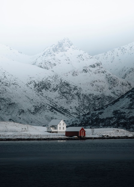 Casa blanca y una cabaña roja junto al lago en invierno.