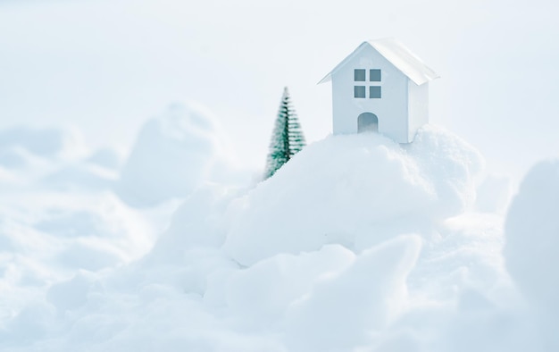 Casa blanca decorativa con un abeto en la nieve a la luz del sol al aire libre espacio libre