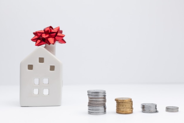 Casa blanca con monedas como concepto de inversión en propiedad. Tomar un préstamo en el banco para comprar una casa.