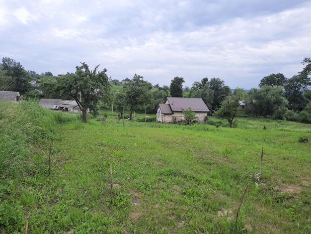 Una casa en un campo con árboles al fondo.