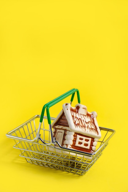 Casa en cesta de metal sobre fondo amarillo, concepto de compra de un apartamento o casa.