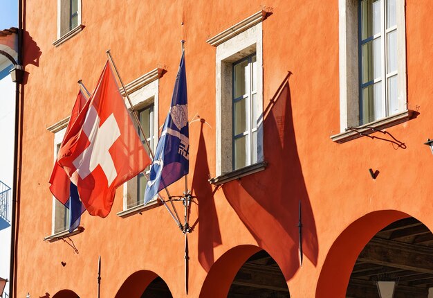 Casa com bandeira suíça no luxuoso resort em Ascona, no Lago Maggiore, no cantão de Ticino, na Suíça. Pessoas no fundo.
