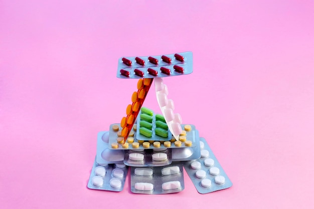 Una casa construida de ampollas con pastillas de varios colores en un espacio de copia de fondo monofónico rosa