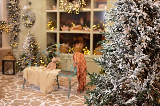 La casa cubierta de nieve está decorada para el nuevo año. Patio de invierno vintage, decorado con adornos de Año Nuevo, árboles de Navidad, linternas y un acogedor banco. Enfoque selectivo suave.