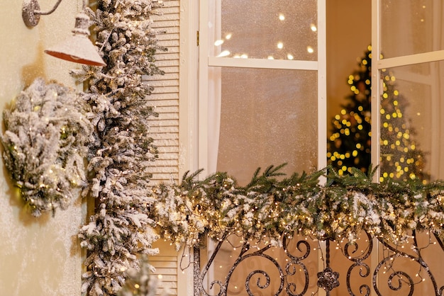 La casa cubierta de nieve está decorada para el nuevo año. Patio de invierno vintage, decorado con adornos de Año Nuevo, árboles de Navidad, linternas de luces. Enfoque selectivo suave.