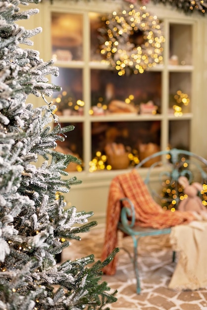 La casa cubierta de nieve está decorada para el nuevo año. Patio de invierno vintage decorado con adornos de Año Nuevo. Árboles de Navidad, faroles, luces y un banco acogedor. Enfoque selectivo suave.