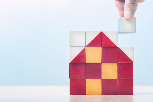 Casa de cubos. en un cuadrado de cubos, el mosaico presentaba una casa. la mano pone el último dado en el mosaico. concepto de negocio de construcción, éxito empresarial, concepto de negocio.