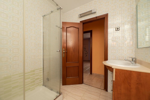 Casa de banho com cabine de duche em vidro com móveis de madeira e portas de madeira escura