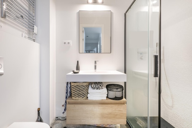 Casa de banho com lavatório monobloco em resina branca cabine de duche com biombos espelhos com finos contornos pretos e gavetas em carvalho