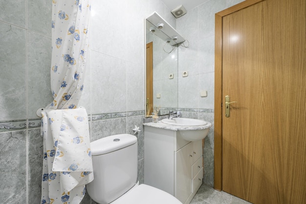 Casa de banho com móvel branco espelho com arandelas porta em madeira de carvalho e ladrilhos bicolores com rebordo