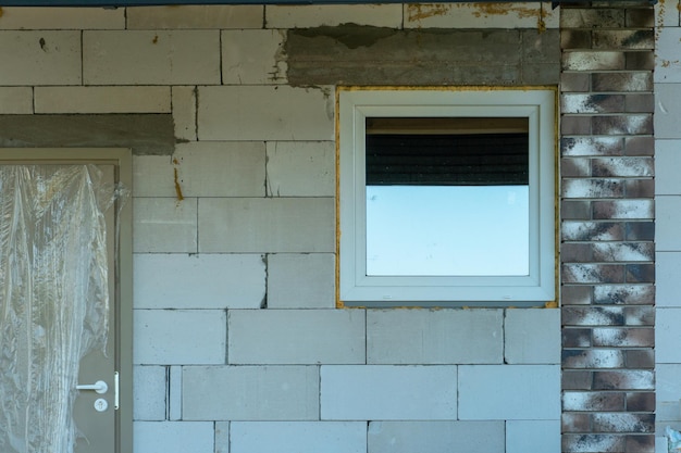 Casa de campo inacabada feita de tijolos de silicato com novas janelas com vidros duplos O processo de construção de uma casa de tijolos