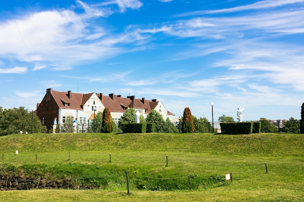 Casa de campo sob céu azul com nuvens brancas e gramado verde