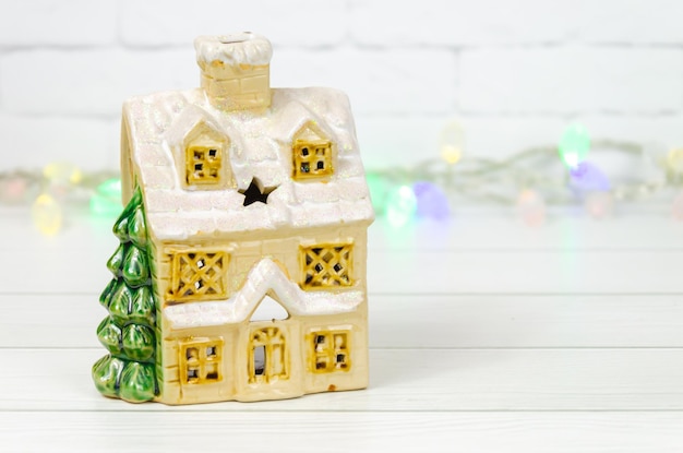 Casa de cerâmica com árvore de Natal na casa de brinquedos vintage de fundo branco com telhado coberto de neve