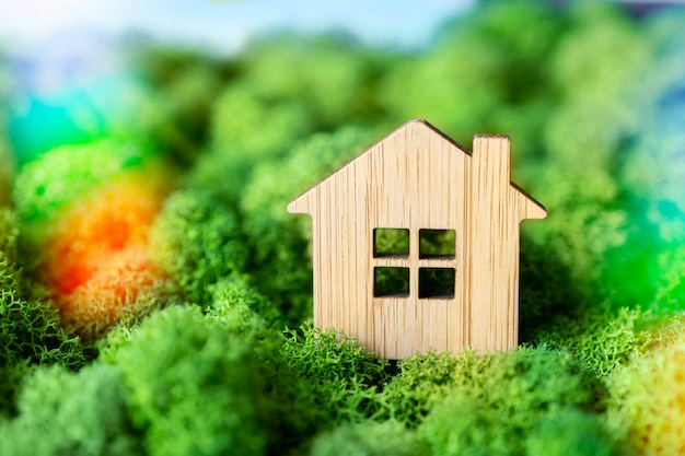 Casa de madeira em miniatura no conceito de musgo verde de venda de seguro ou aluguel de imóveis