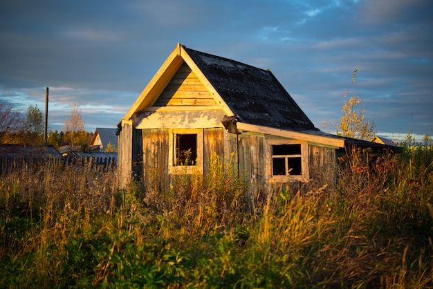 Casa de madeira velha da vila coberta de grama, Urais, agosto