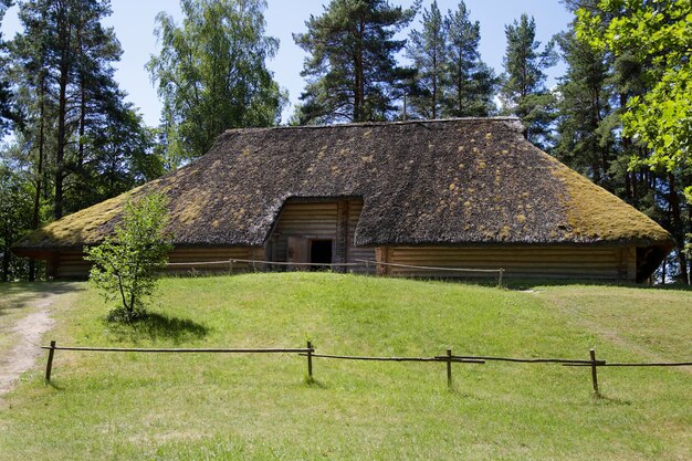 Casa de madeira velha tradicional com telhado de junco na Letônia