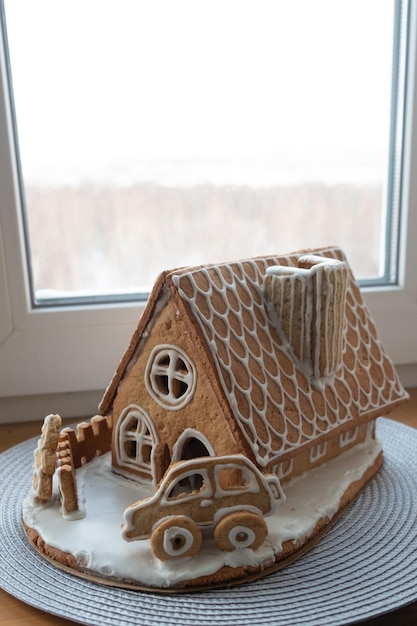 Foto casa de natal feita de biscoitos de gengibre com carro de gengibre do lado de fora decorado com espírito natalino