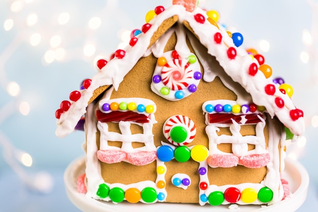 Casa de pão de mel decorada com glacê real branco e doces brilhantes.