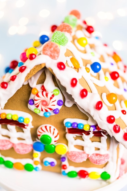 Casa de pão de mel decorada com glacê real branco e doces brilhantes.