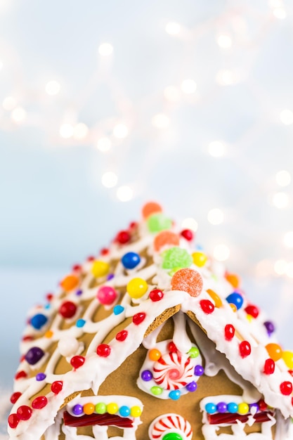 Casa de pão de mel decorada com glacê real branco e doces brilhantes.