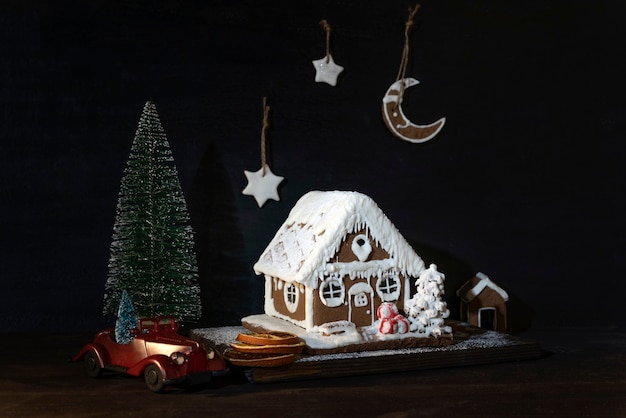 Casa de pão de mel e biscoitos ao lado do carro de brinquedo e uma pequena árvore de Natal. Feliz Natal e Feliz Ano Novo.