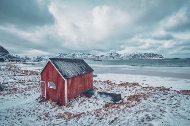 Casa de rorbu vermelho na praia de um fiorde na Noruega