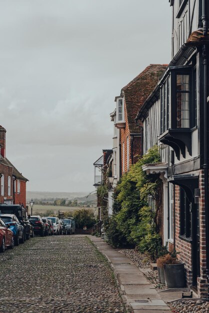 Casa de terraços velha em uma rua de paralelepípedos em Rye UK carros estacionados em frente