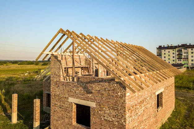 Casa de tijolos inacabada com estrutura de telhado de madeira em construção.