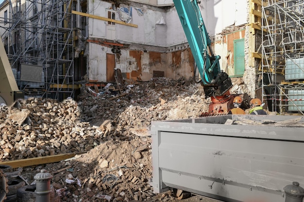 Casa destruida en ruinas Una excavadora destruye una casa con un balde