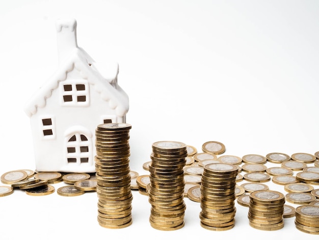 Casa e pilha de moedas no conceito de poupança de hipoteca de fundo branco