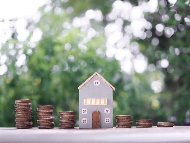 Casa em miniatura e pilha de moedas O conceito de economizar dinheiro para a casa Investimento imobiliário Hipoteca imobiliária Real estste