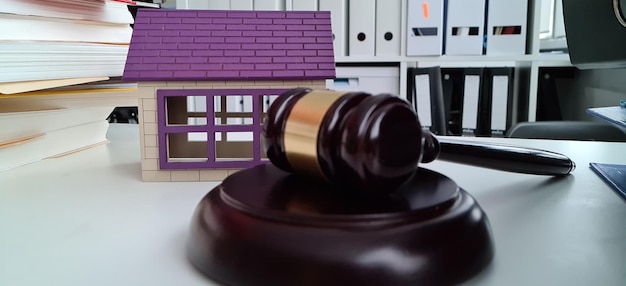 Casa em miniatura na mesa ao lado do martelo do tribunal