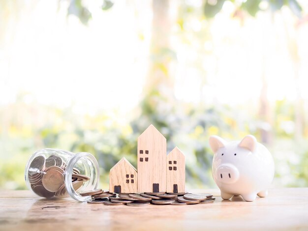 Casa em miniatura na pilha de moedas e cofrinho para o conceito de propriedade de investimento Economizando dinheiro para comprar uma casa
