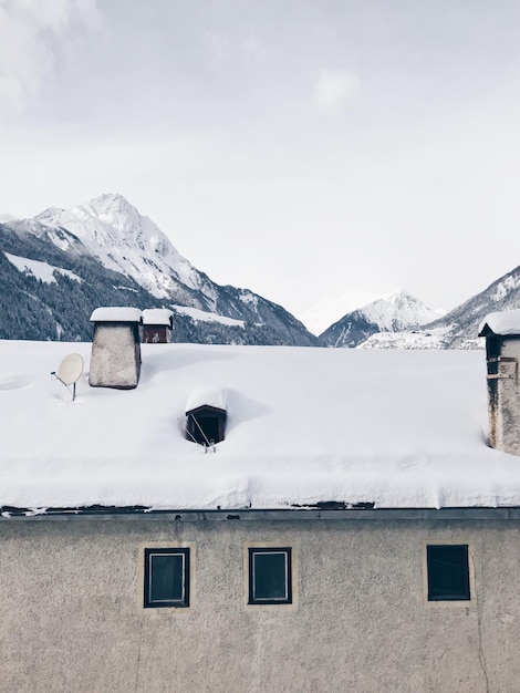 Foto casa em montanhas cobertas de neve contra o céu