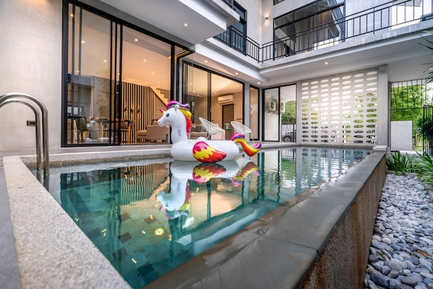 Casa exterior con piscina y unicornio flotante en la casa