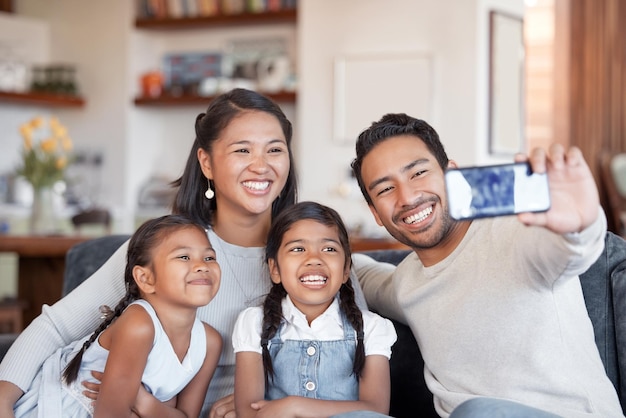 Casa de familia asiática y selfie de niños felices con padres por conexión de amor y unión juntos Niños mamá y papá tomando fotos con hermanas en el sofá para fotografía de memoria o redes sociales