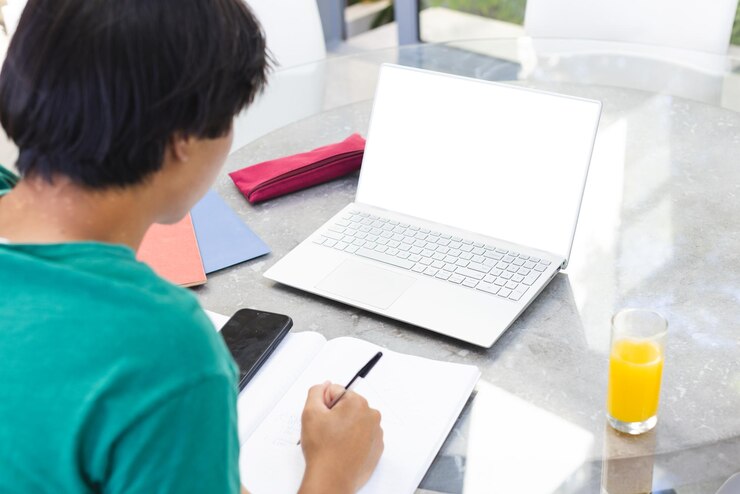 Foto en casa, fuera, un adolescente asiático escribiendo en un portátil, un espacio abierto para copiar.