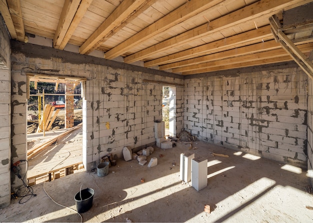 Casa habitación interior en construcción y renovación. Paredes ahorradoras de energía de bloques de aislamiento de espuma hueca, vigas de madera en el techo y marco del techo.