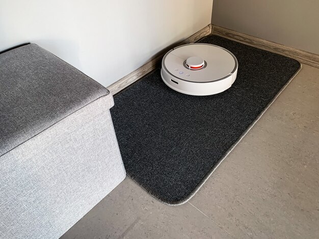 Casa inteligente. El robot aspirador funciona en el piso de una sala de estar.