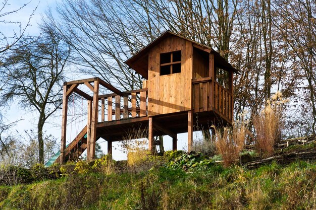 Casa de juegos infantil de madera de bricolaje con columpio y tobogán en la ladera