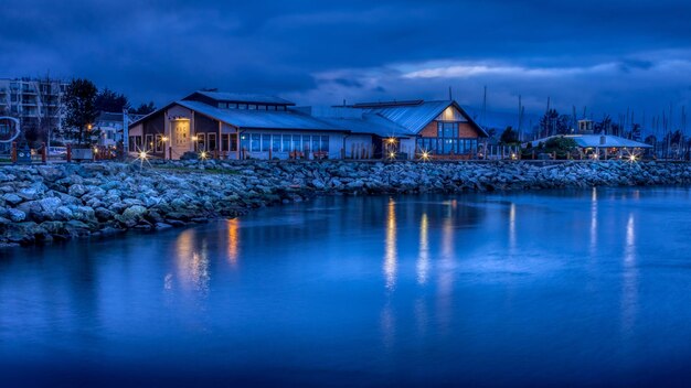 una casa junto al agua con un cielo azul y una luz en él