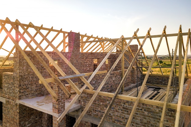 Casa de ladrillo sin terminar con estructura de techo de madera en construcción.